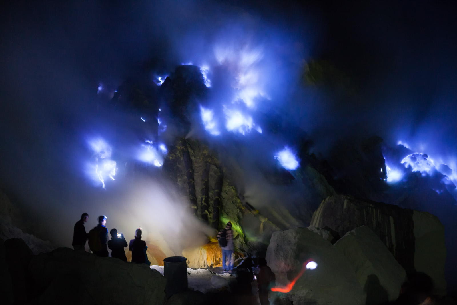 Silhouette of tourists looking into the blue fire a flow of liquid sulfur which has caught fire and burns with an blue flame. Cater of the Kawah Ijen volcano, Java, Indonesia.